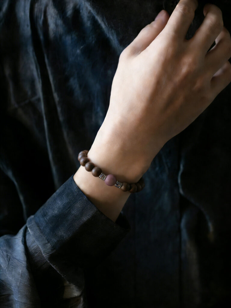 Woman wearing Butterfly scent in Spring Moon bracelet on wrist, showing smooth polished beads and soft luster, natural light, daily wear scene