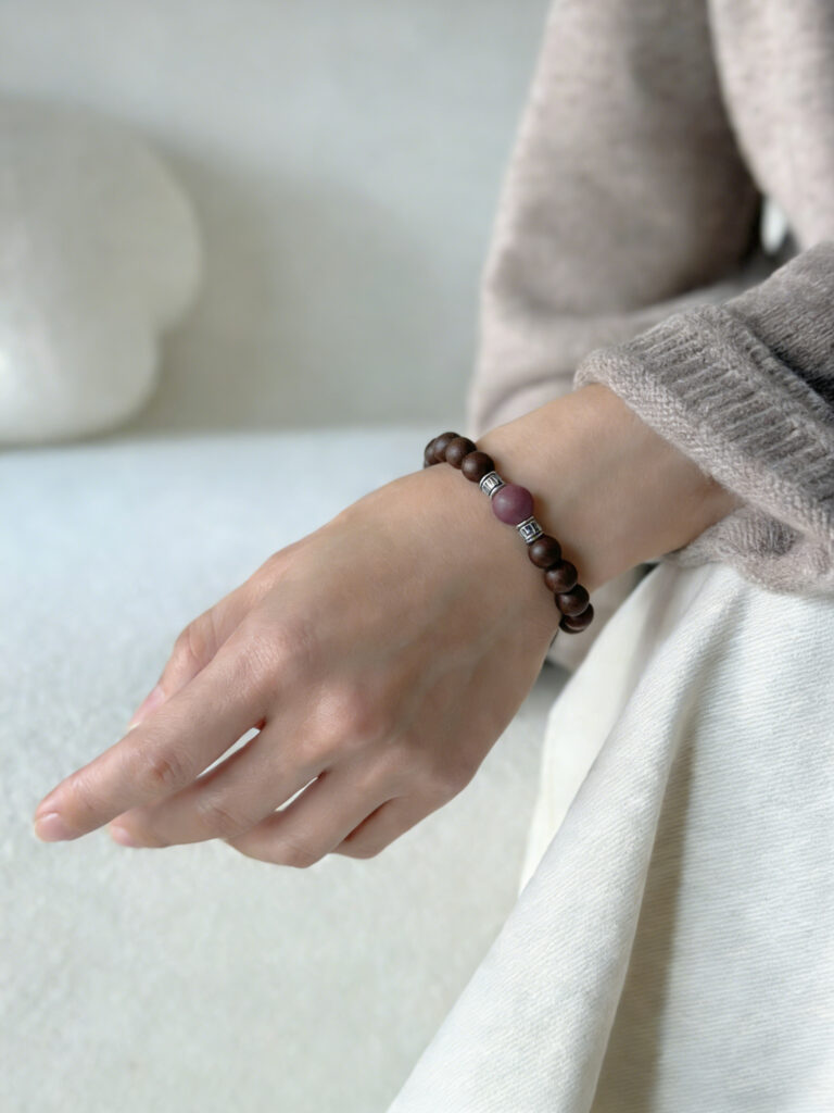 A flat lay of the Butterfly Scent in Spring Moon bracelet, surrounded by its core natural ingredients (dried herbs and sandalwood pieces), paired with a small card that reads "Natural Wellness, Wearable Everywhere".